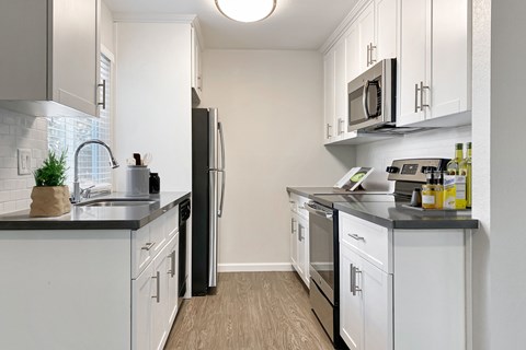 A kitchen with white cabinets and black countertops.