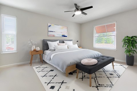 A bedroom with a large bed, a ceiling fan, and a rug on the floor.