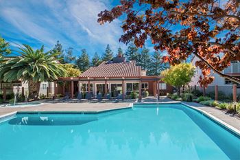 A swimming pool surrounded by trees and a building with a red roof at Valley Plaza Villages, Pleasanton, California
