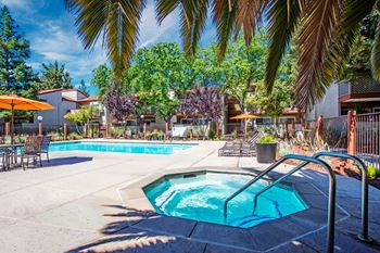 A pool surrounded by palm trees and patio furniture at Valley Plaza Villages, Pleasanton, California
