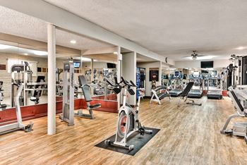 a gym with cardio machines and weights on a wooden floor