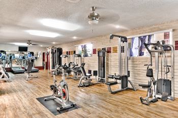a gym with weights and cardio equipment on a wood floor