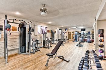 a gym with cardio machines and weights on a wooden floor