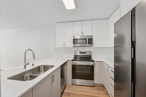 A modern kitchen with stainless steel appliances and white cabinetry.