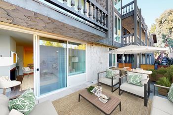 A patio with a table and chairs is surrounded by a white wall.