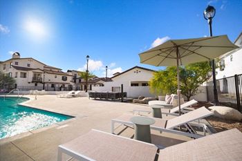 a pool with chairs and umbrellas next to a house at The Villas at Anacapa Canyon, Camarillo