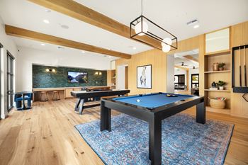 A pool table in a room with wooden floors and a television in the background at The Villas at Anacapa Canyon, Camarillo