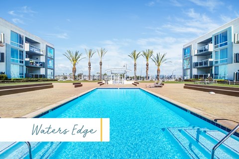 A large swimming pool in front of a building with the name Waters Edge.