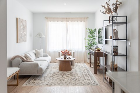 A living room with a white sofa, a wooden coffee table, and a rug on the floor.