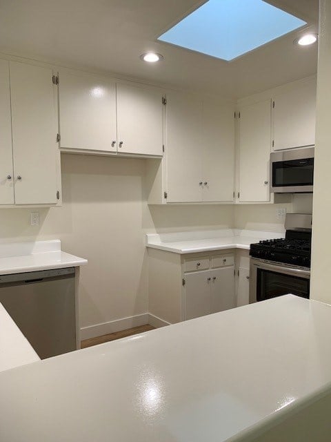 an empty kitchen with white cabinets and a white counter top