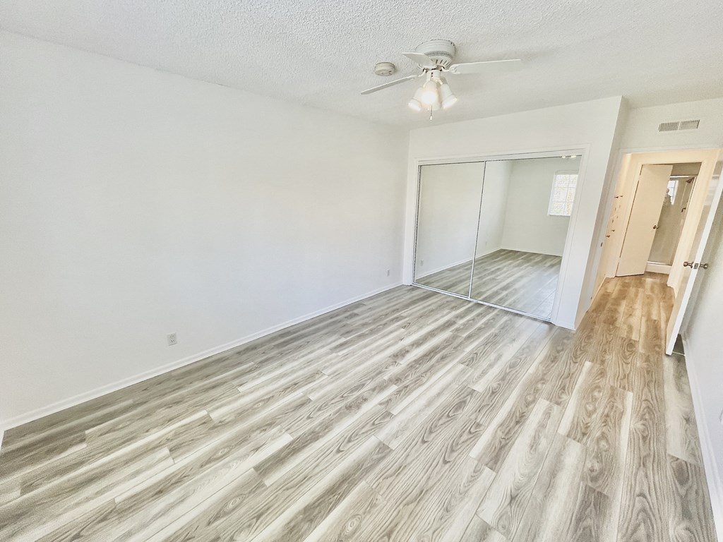 Bedroom with Hardwood Floors, Mirrored Wardrobe Closet and Fan