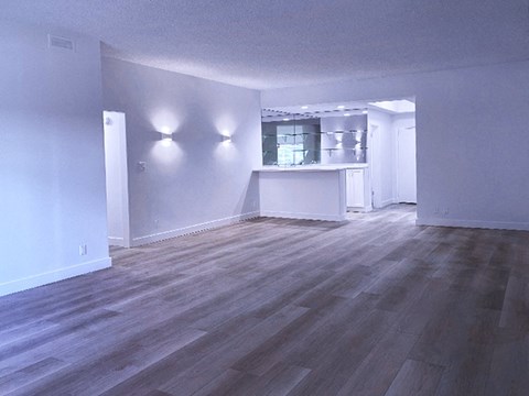 an empty living room and kitchen with a wood floor