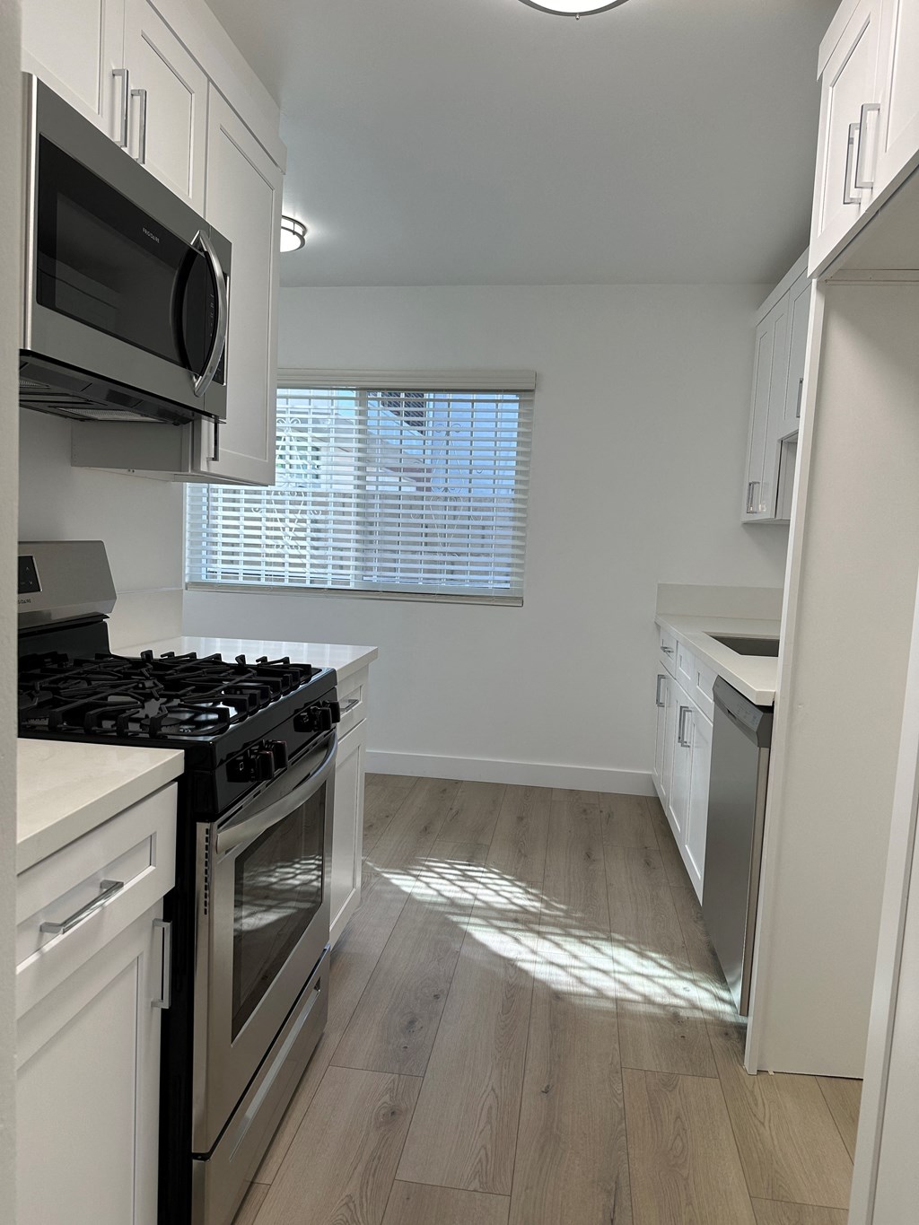 Kitchen with Hardwood Floors, White Cabinets and Stainless Steel Appliances