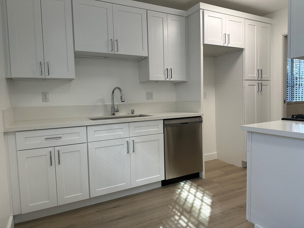 Kitchen with Hardwood Floors, White Cabinets and Stainless Steel Appliances