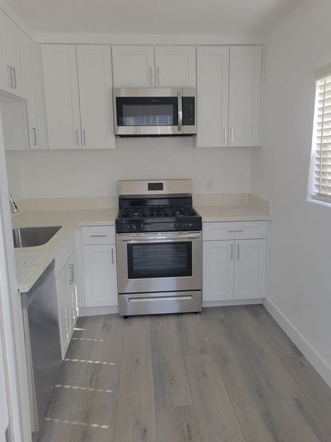 a kitchen with white cabinets and a stainless steel stove and microwave