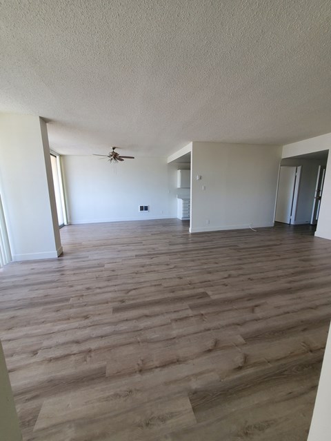 an empty living room with wooden floors and a ceiling fan
