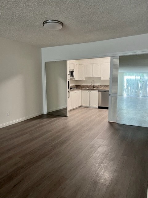 an empty living room and kitchen with wood floors