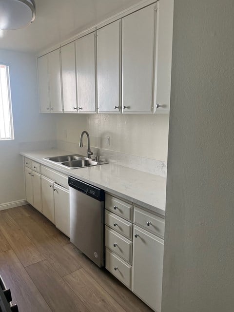 a kitchen with white cabinets and a sink and a dishwasher