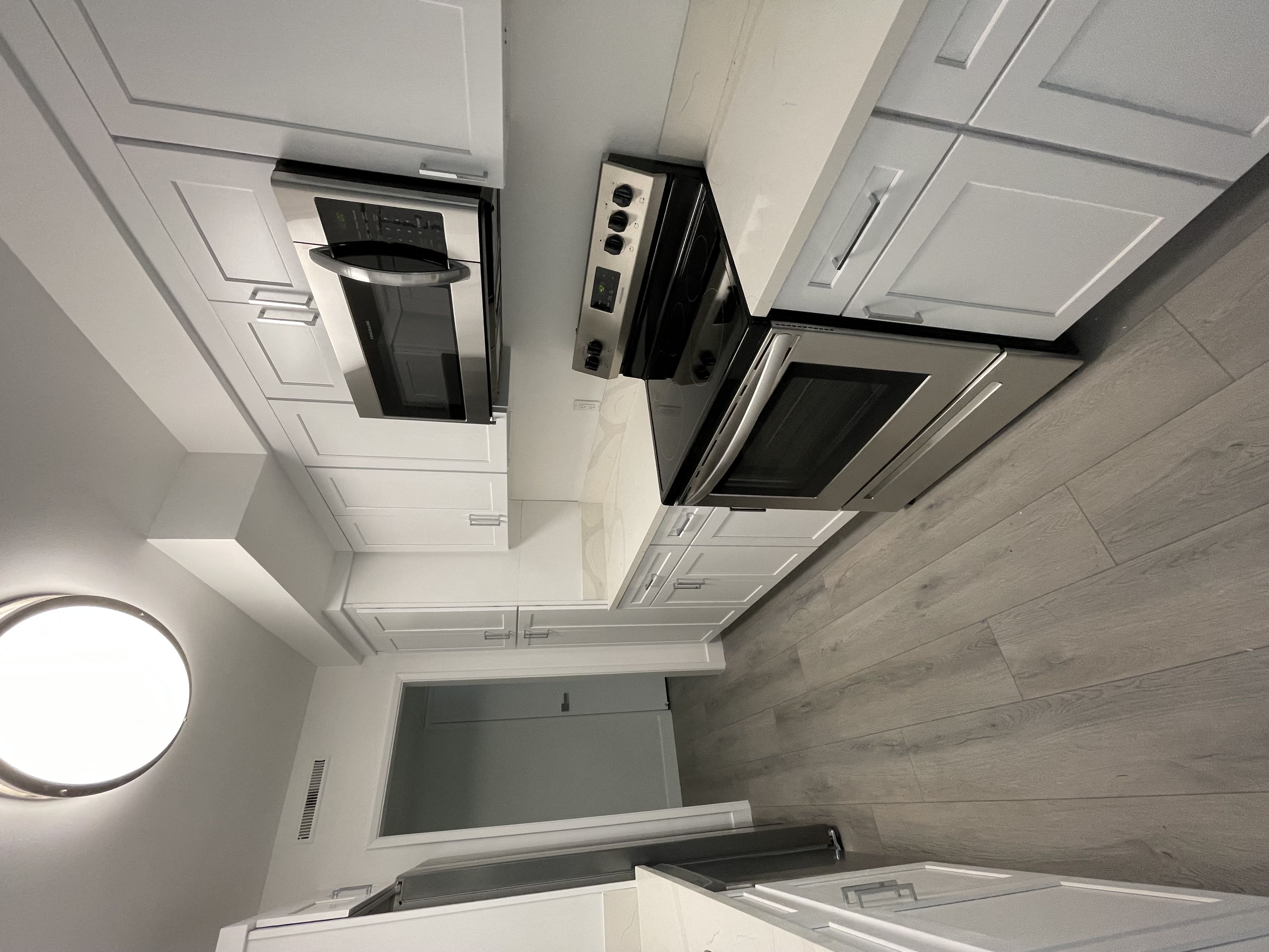 a kitchen with white cabinets and two microwaves on the ceiling