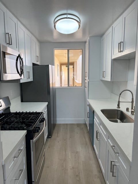 a renovated kitchen with white cabinets and a sink