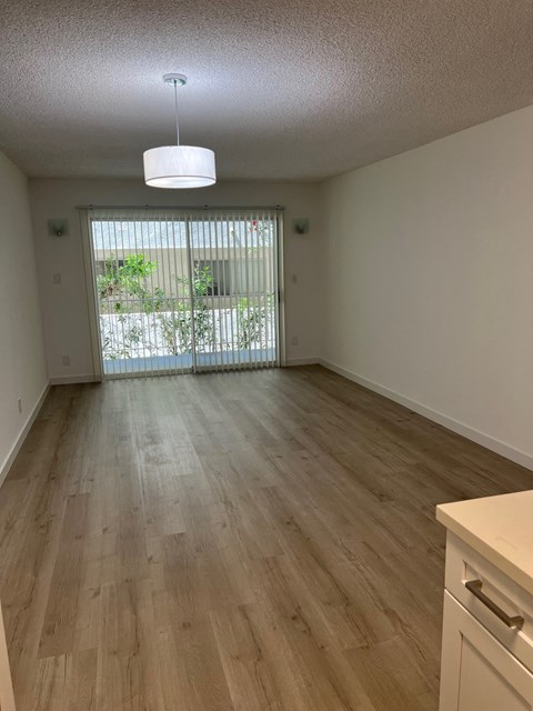 an empty living room with wood floors and a window