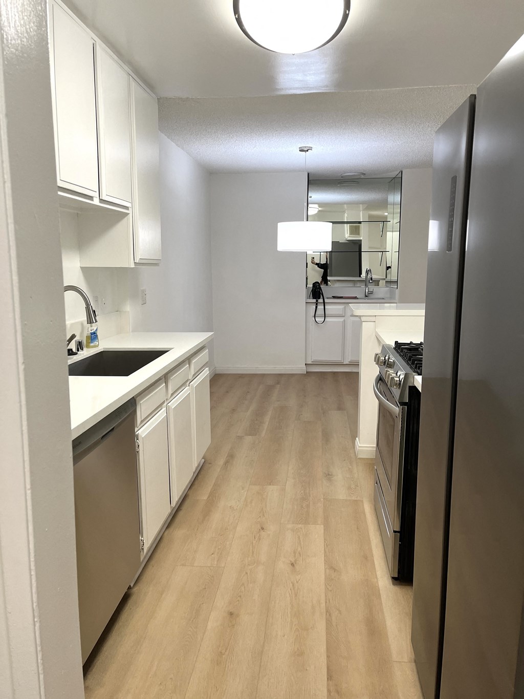 Kitchen with Hardwood Floors, White Cabinets and Stainless Steel Appliances