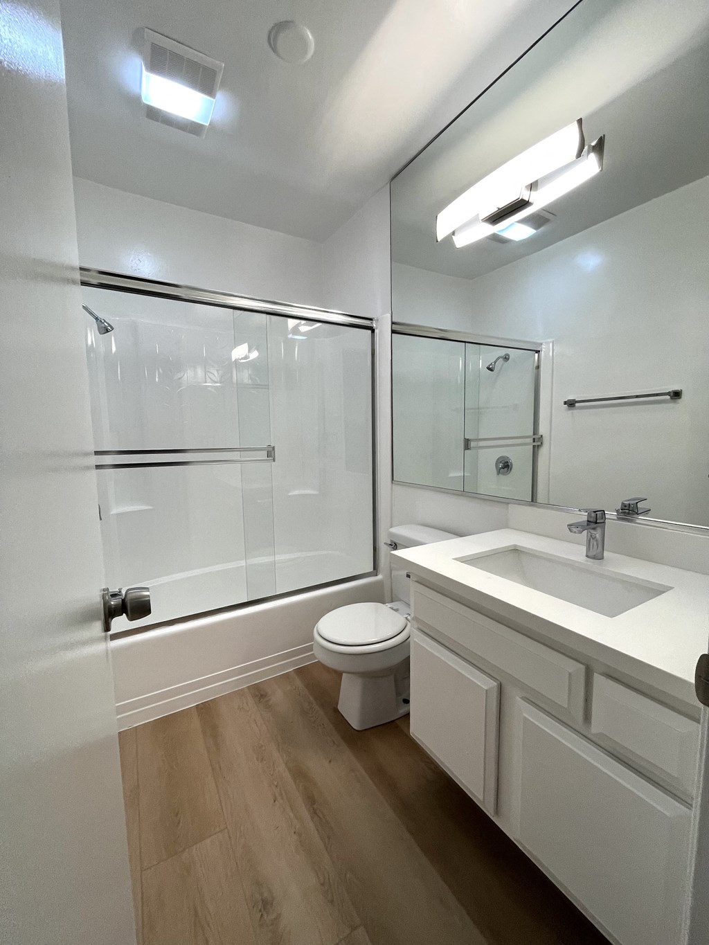 Bathroom with Hardwood Floors, White Cabinets and Bathtub/Shower