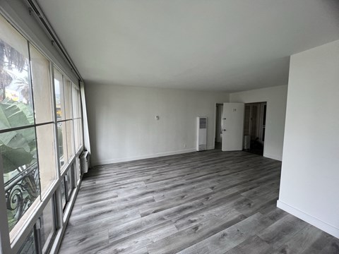 an empty living room with wood floors and white walls