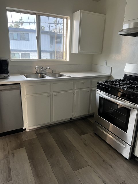 a kitchen with white cabinets and a stove and a sink