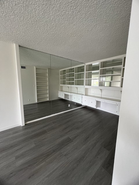 an open living room with wood flooring and white shelves