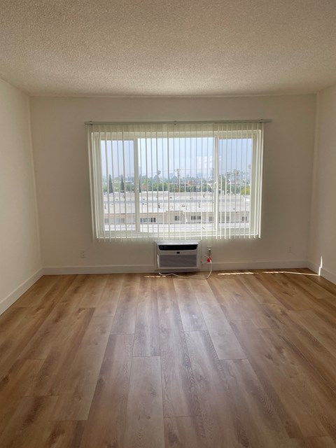 an empty living room with wood floors and a window