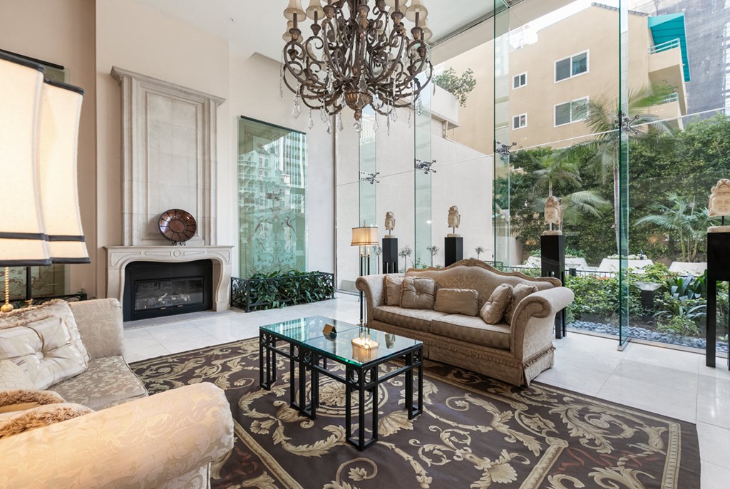 A lobby with a fireplace, a sofa, a coffee table, and a chandelier.