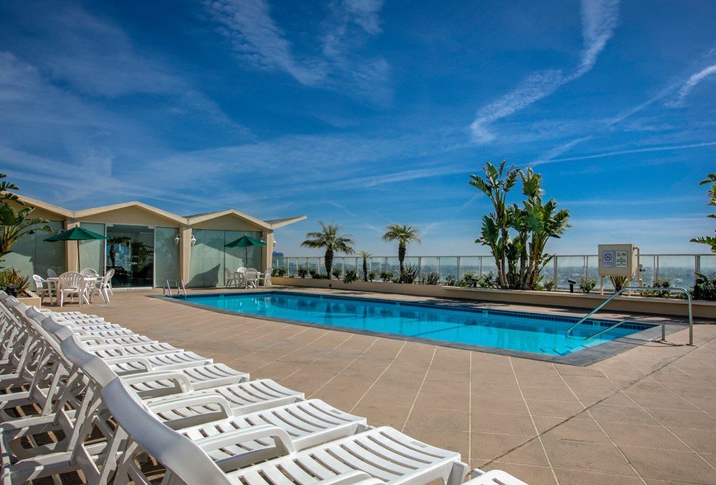 A poolside area with sun loungers and a building in the background.