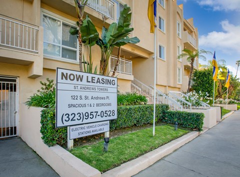 a now leasing sign in front of an apartment building