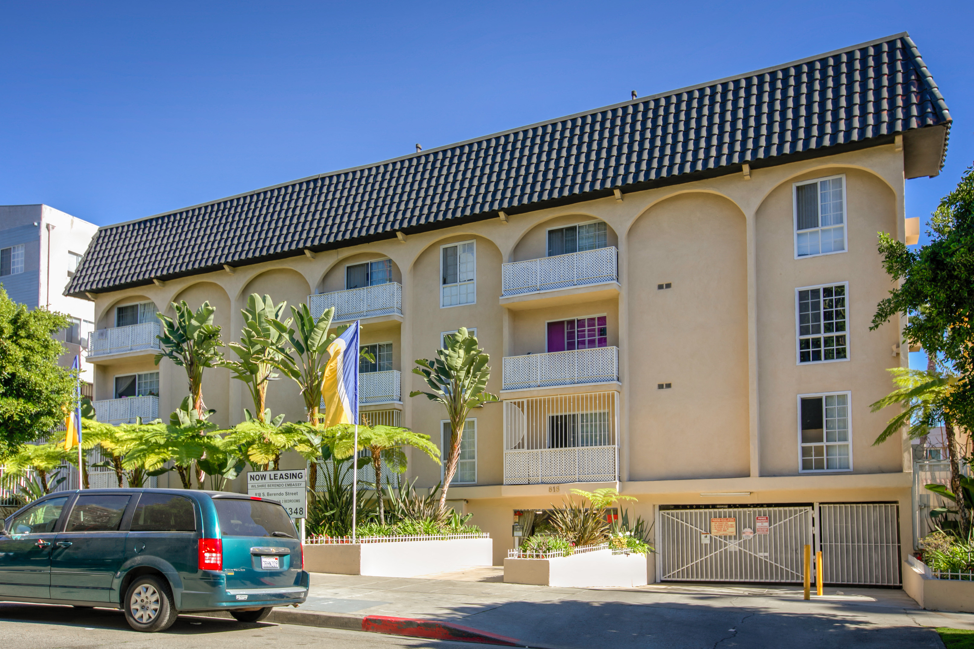 a van parked in front of an apartment building with palm trees