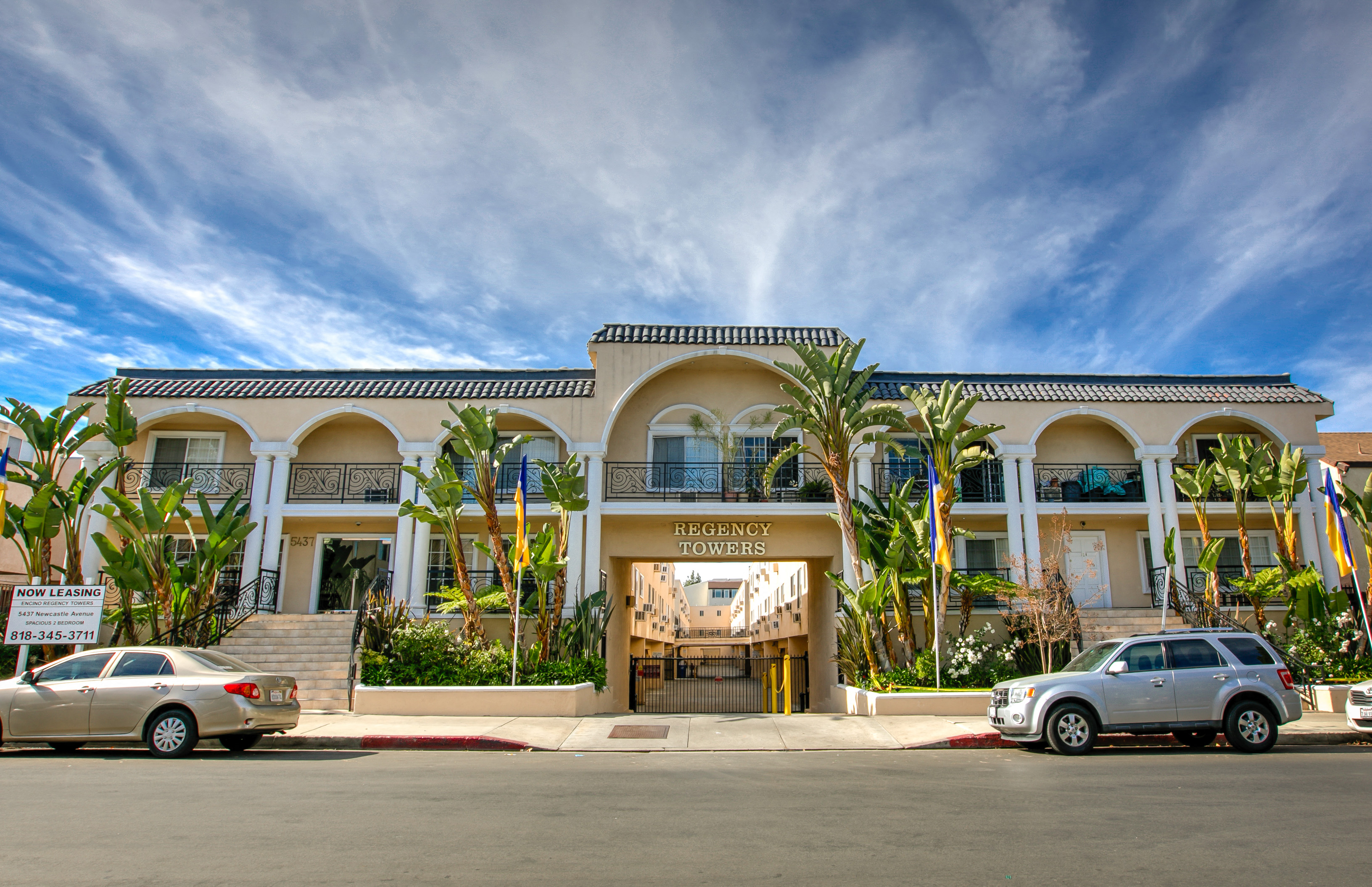 a building with palm trees and cars parked in front of it