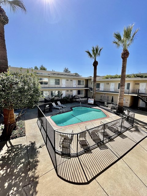 a resort style pool with palm trees and a building in the background