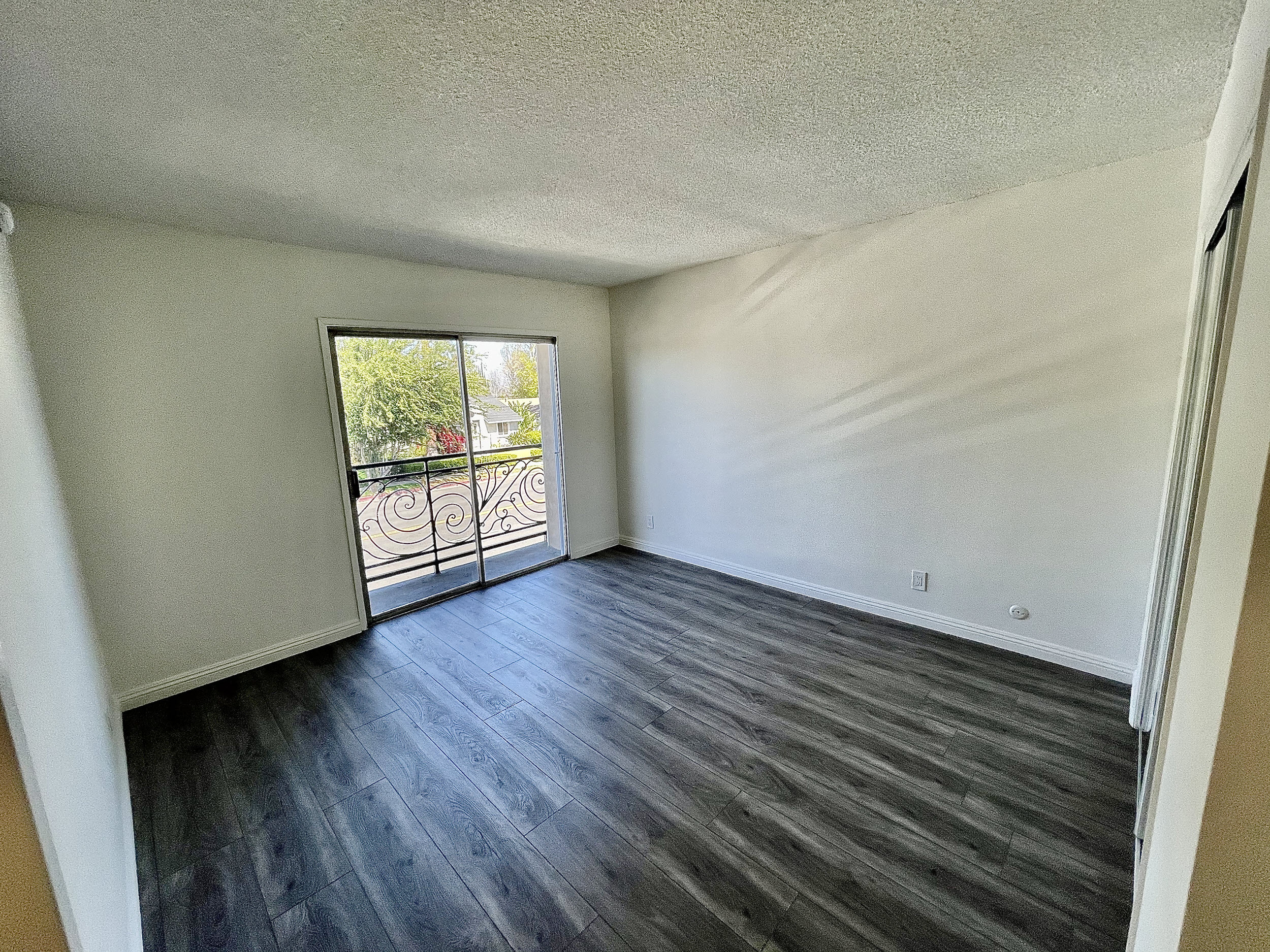 an empty living room with wood flooring and a balcony