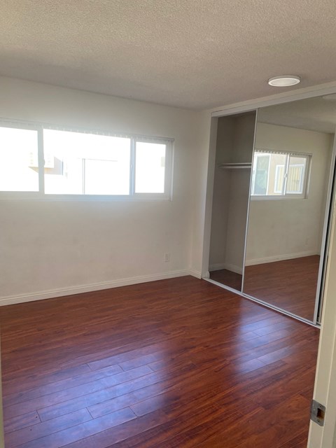 an empty living room with wood floors and a mirrored closet