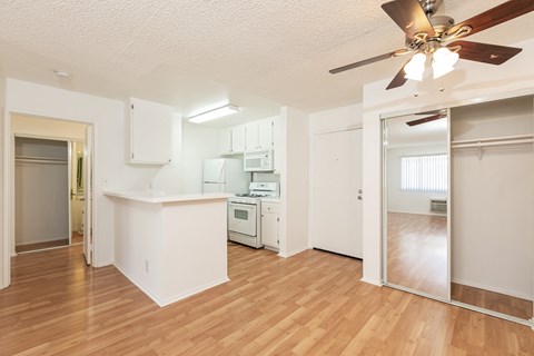 an empty living room and kitchen with a ceiling fan