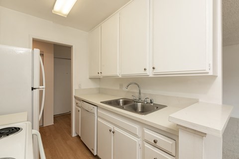 a kitchen with white cabinets and a sink and a refrigerator