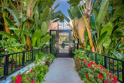 a gate in a garden with flowers and plants
