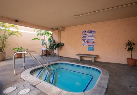 a hot tub in a building with a wall with a painting on it