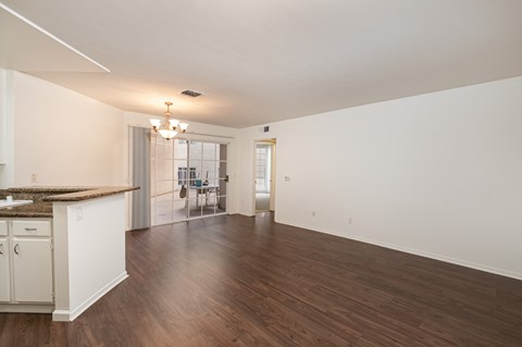 the living room and dining room of an empty house with wood floors and white walls