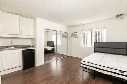 a bedroom with a bed and a kitchen with a sliding glass door