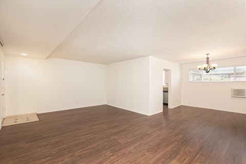 an empty living room with a hard wood floor and white walls