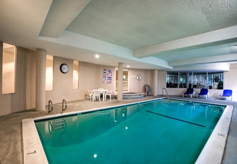 a swimming pool in a room with chairs and a clock