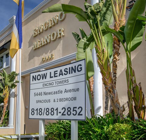a now leasing sign in front of a building