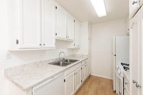 a kitchen with white cabinets and marble counter tops and a sink