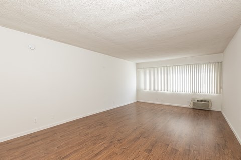 an empty living room with wood floors and white walls